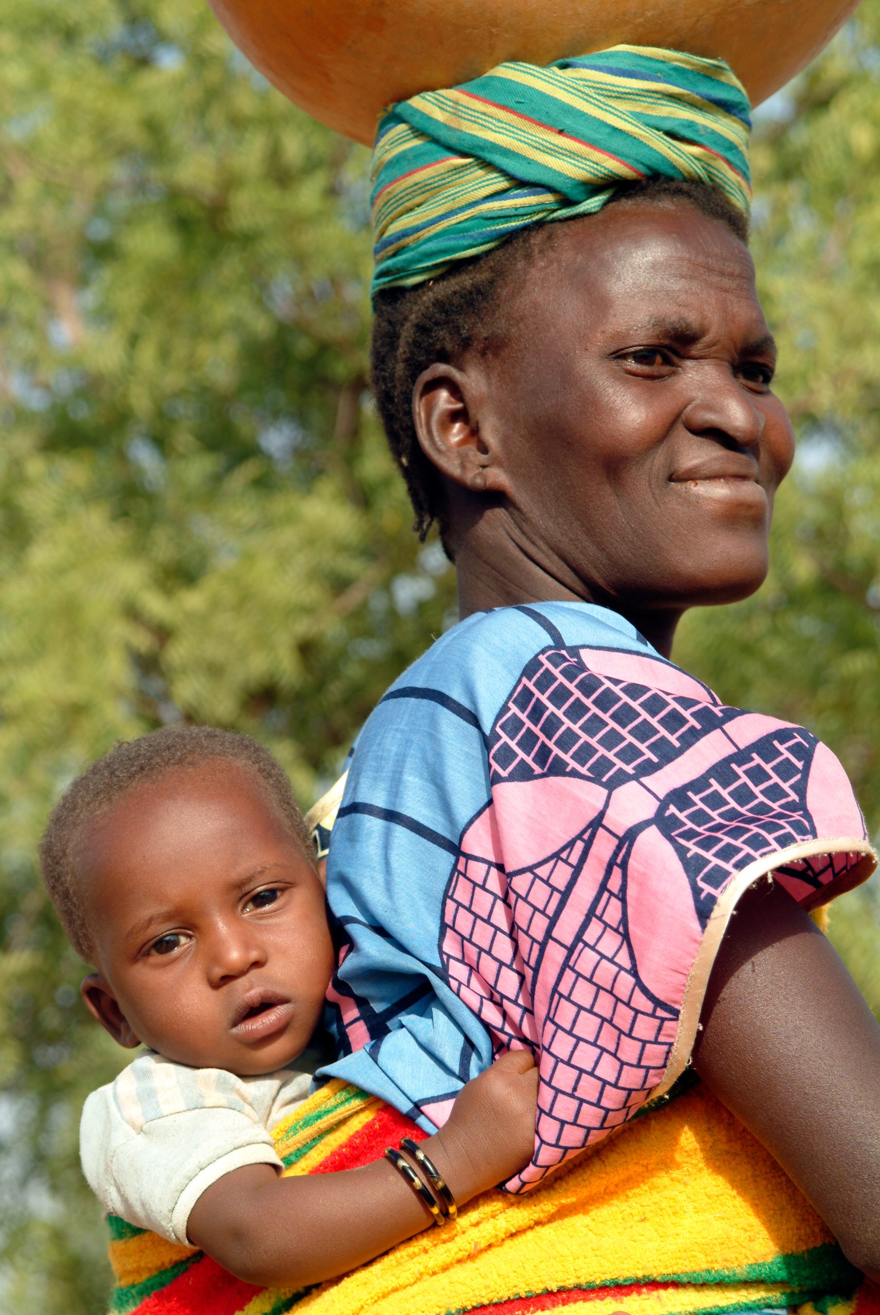 Une maman qui porte son enfant avec un pagne.