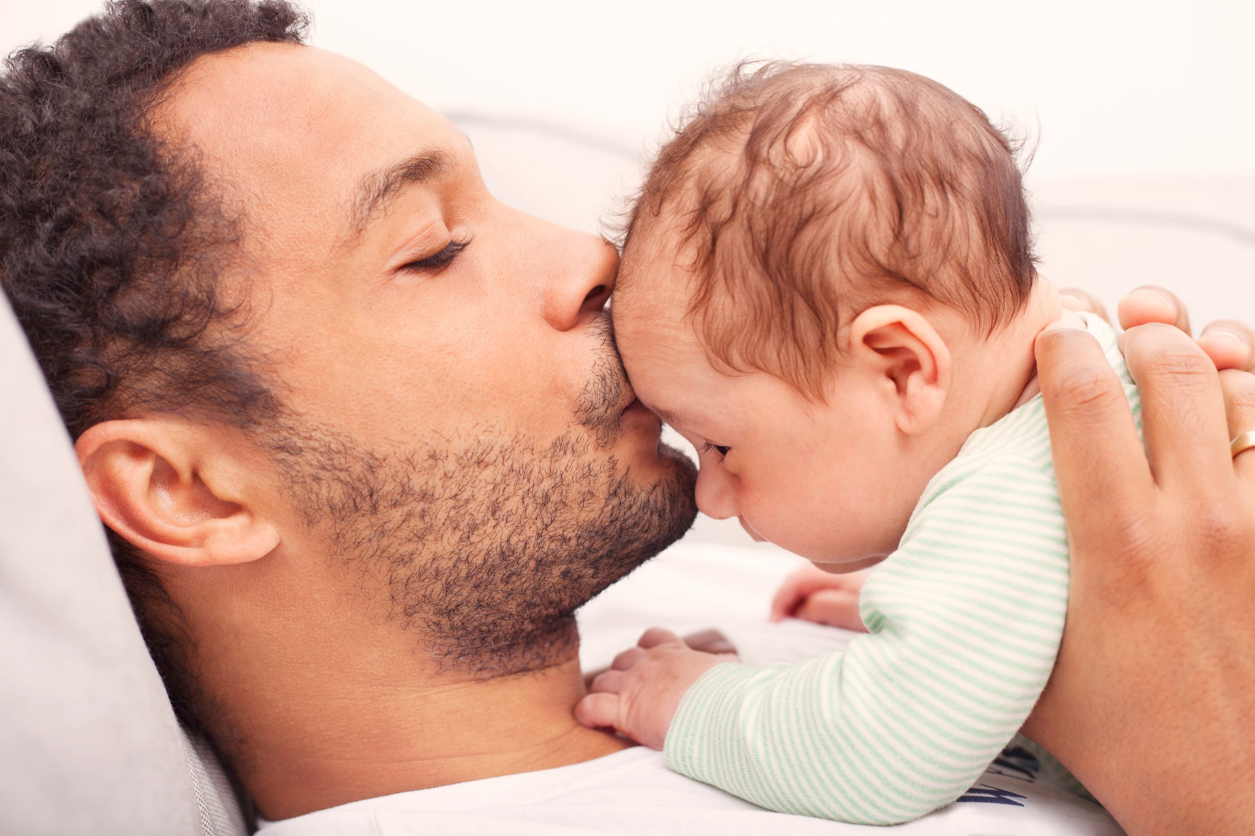 Un père qui embrasse sur le front son enfant.