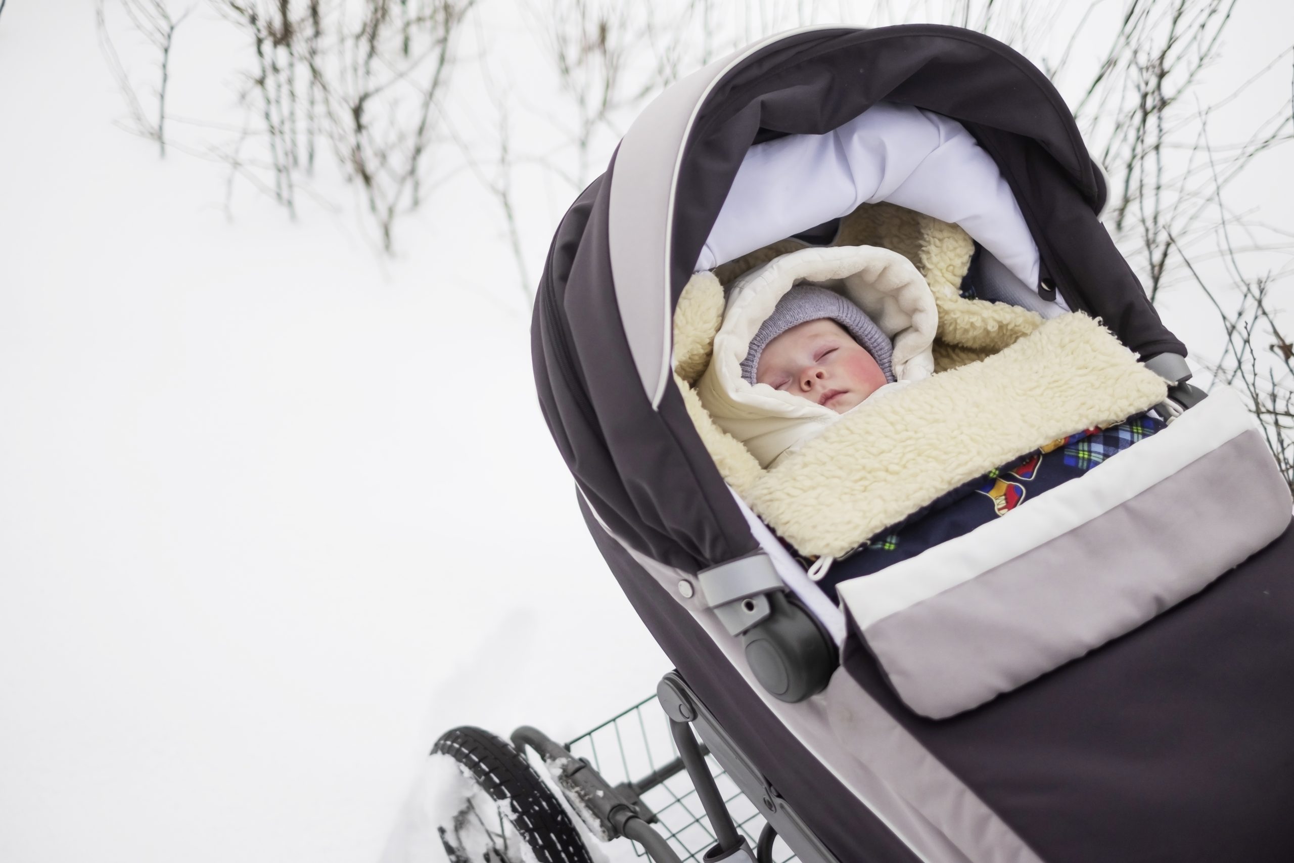 Bébé qui dort dans sa poussette un jour de neige.