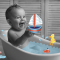 Bébé dans son bain entouré de jouets illustrés.